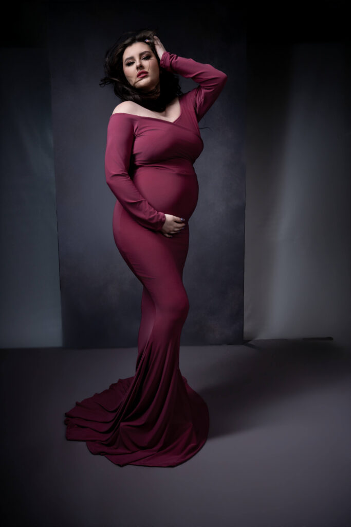 Glamorous maternity portrait in dark pink dress